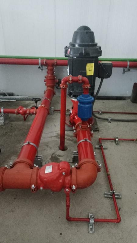 Bomba contra incendios instalada con tuberías rojas.