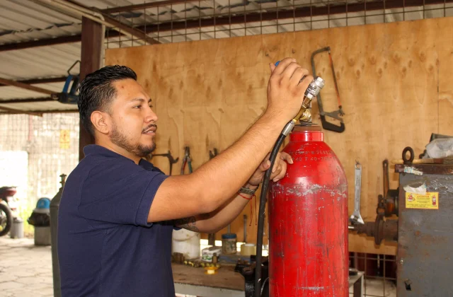 Técnico conectando tanque de gas rojo.